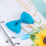 Turquoise bow paperclip bookmark on cocoa daisy planner kit