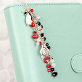 Penguin Planner Charm Dangle with Red, White and Black Crystals shown on ring bound planner